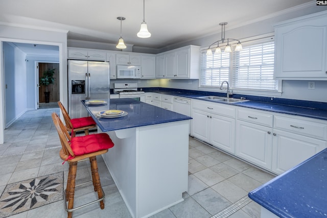 kitchen featuring decorative light fixtures, a center island, white appliances, and white cabinetry