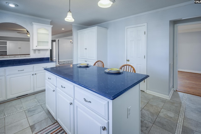 kitchen with ceiling fan, crown molding, white cabinets, and a kitchen island