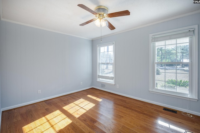 spare room featuring wood-type flooring, ornamental molding, a healthy amount of sunlight, and ceiling fan