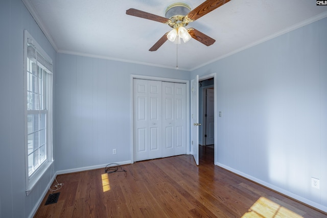 unfurnished bedroom featuring hardwood / wood-style floors, ceiling fan, ornamental molding, and a closet