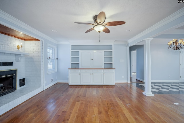 unfurnished living room featuring a brick fireplace, light wood-type flooring, a textured ceiling, ceiling fan with notable chandelier, and ornamental molding