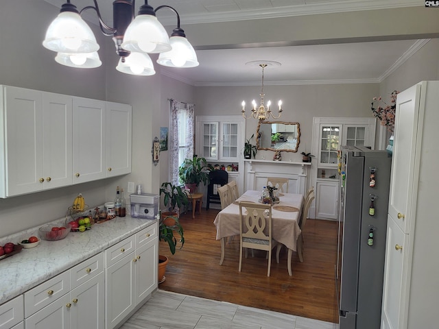 kitchen with stainless steel refrigerator, light stone counters, light hardwood / wood-style flooring, a notable chandelier, and white cabinets