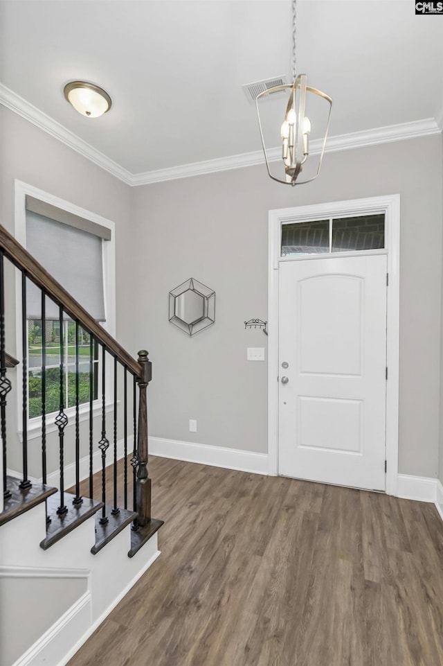 foyer featuring wood-type flooring, ornamental molding, and a chandelier