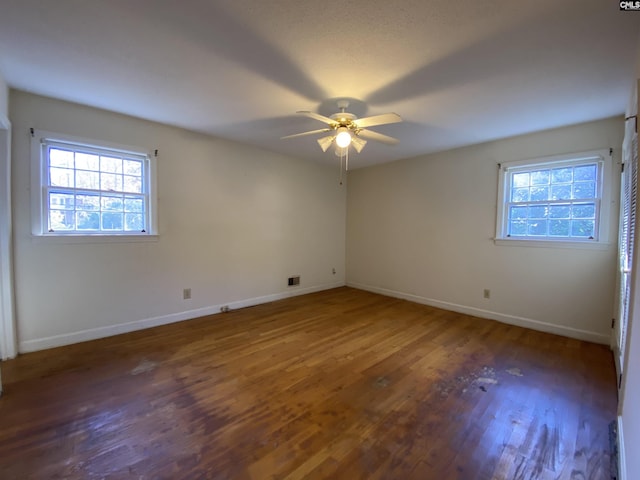 spare room featuring ceiling fan, dark wood-type flooring, and a healthy amount of sunlight