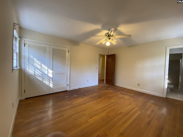 unfurnished bedroom with ceiling fan, ensuite bathroom, and dark wood-type flooring