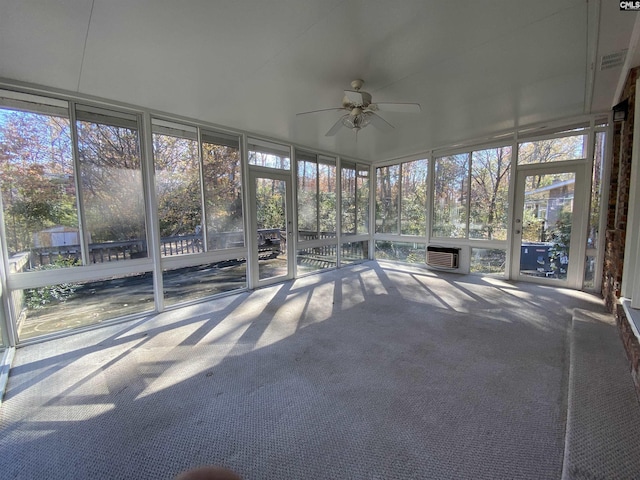 unfurnished sunroom featuring a wall unit AC, ceiling fan, and a healthy amount of sunlight