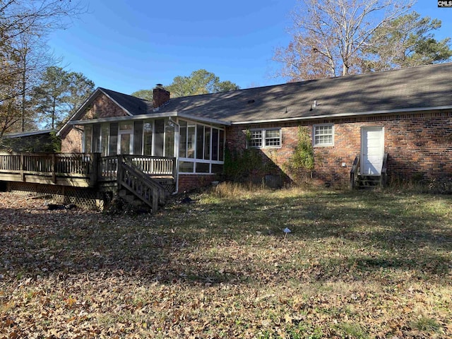 back of house featuring a sunroom, a yard, and a wooden deck