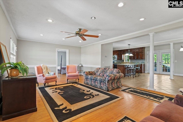 living room with crown molding, light hardwood / wood-style flooring, ceiling fan, and a textured ceiling