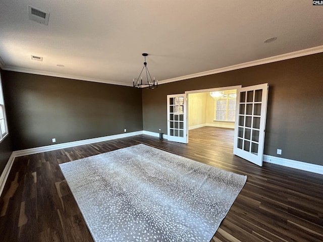 unfurnished room featuring a chandelier, ornamental molding, french doors, and dark wood-type flooring