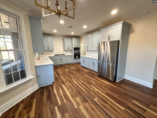 kitchen with appliances with stainless steel finishes, crown molding, sink, a chandelier, and dark hardwood / wood-style floors