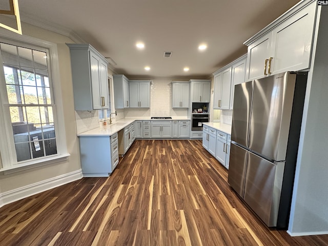 kitchen featuring sink, dark wood-type flooring, backsplash, gray cabinets, and appliances with stainless steel finishes