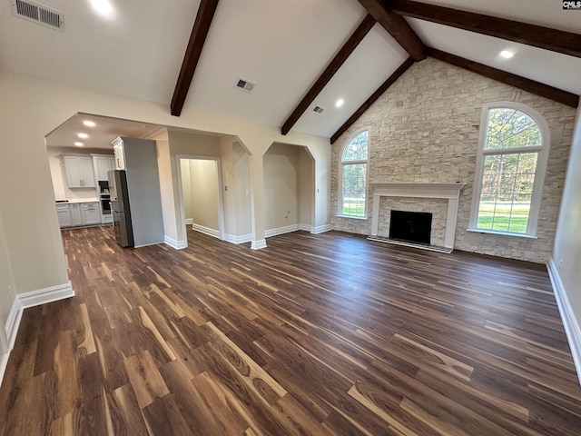 unfurnished living room with dark hardwood / wood-style floors, beam ceiling, a fireplace, and high vaulted ceiling