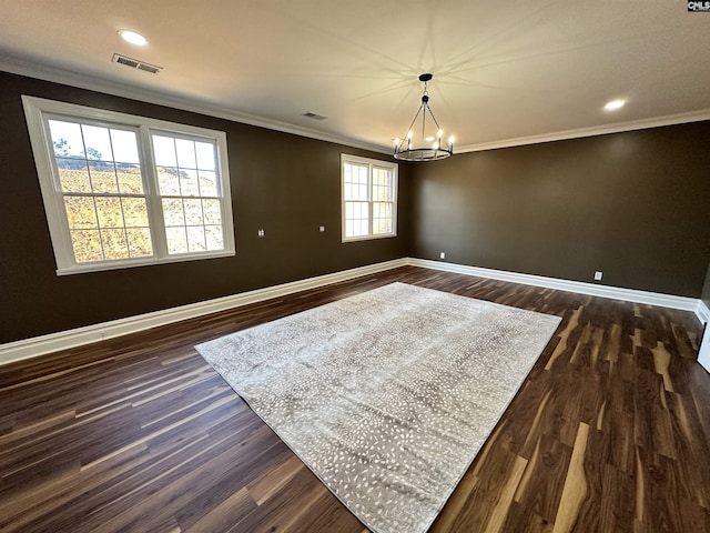 empty room featuring crown molding, dark wood-type flooring, and an inviting chandelier