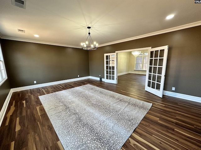 spare room featuring dark hardwood / wood-style flooring, french doors, crown molding, and a chandelier