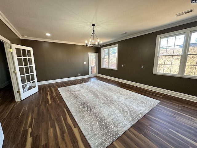 empty room featuring ornamental molding, dark wood-type flooring, and a chandelier