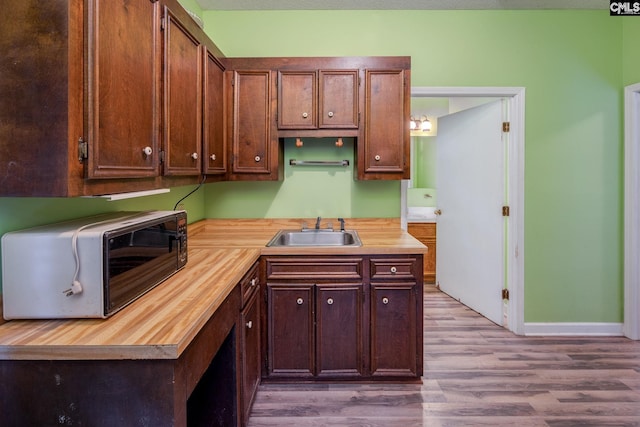 kitchen featuring butcher block counters, sink, a chandelier, and light hardwood / wood-style flooring