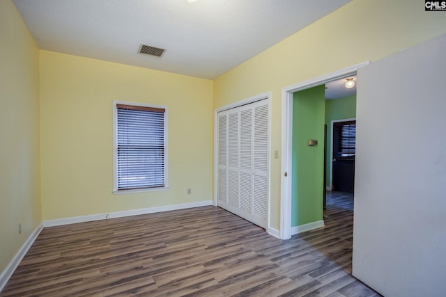 unfurnished bedroom featuring a closet, a textured ceiling, and hardwood / wood-style flooring