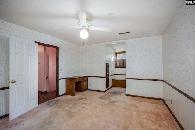 empty room with light carpet, ceiling fan, and a textured ceiling