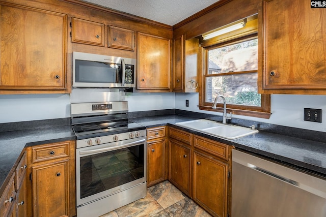 kitchen featuring a textured ceiling, stainless steel appliances, and sink