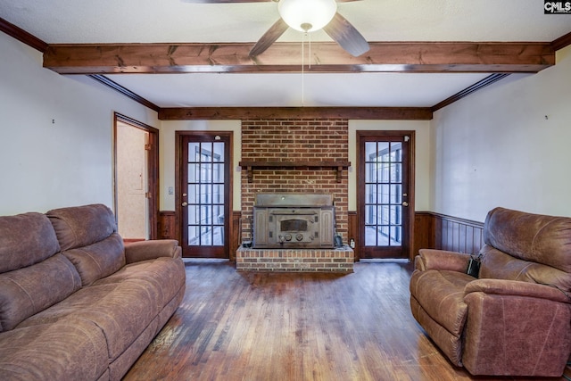 living room featuring wooden walls, ceiling fan, ornamental molding, beam ceiling, and dark hardwood / wood-style flooring