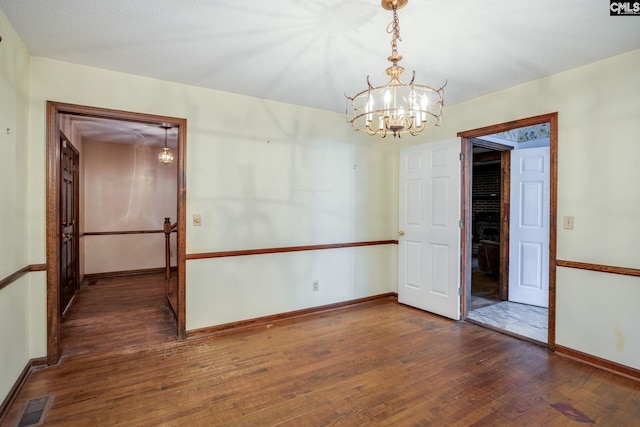 empty room featuring dark hardwood / wood-style floors and a chandelier