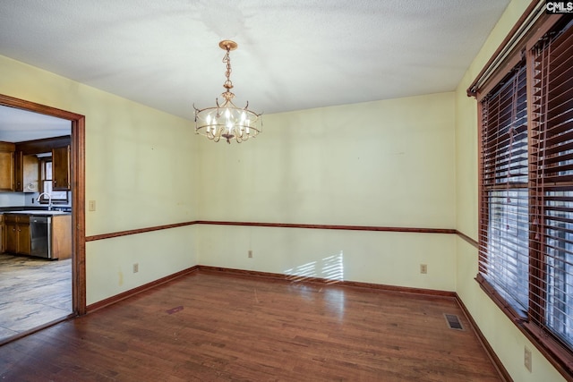 unfurnished dining area with hardwood / wood-style floors, a textured ceiling, and a chandelier