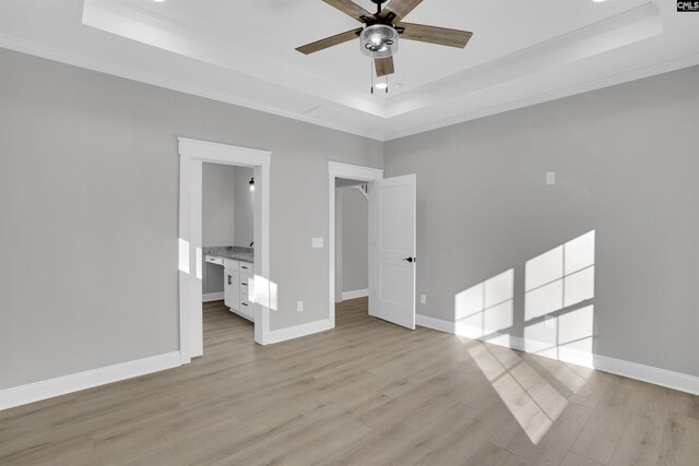 unfurnished bedroom featuring a raised ceiling, ceiling fan, light hardwood / wood-style flooring, and ornamental molding