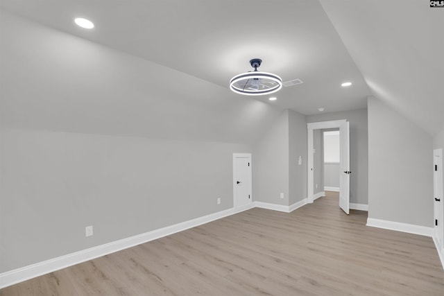 additional living space with vaulted ceiling and light hardwood / wood-style flooring