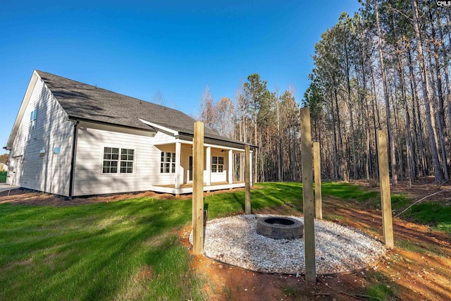 rear view of house with a fire pit, a wooden deck, and a lawn