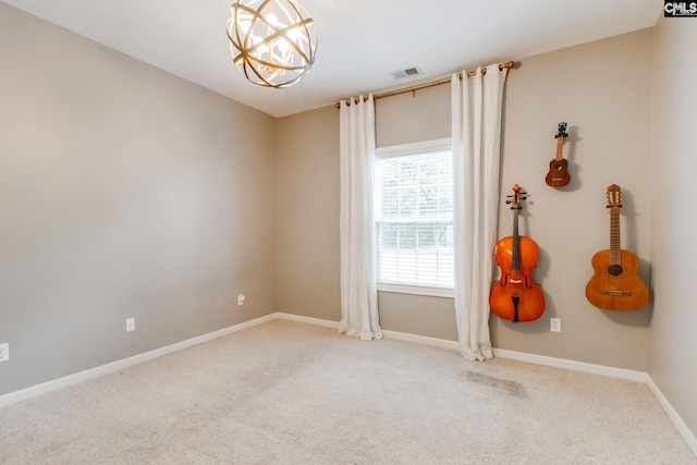 carpeted empty room featuring a notable chandelier, visible vents, and baseboards