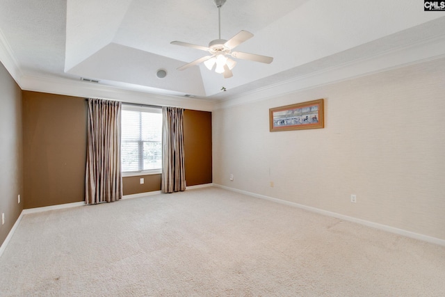 carpeted spare room featuring ceiling fan, visible vents, baseboards, ornamental molding, and a raised ceiling