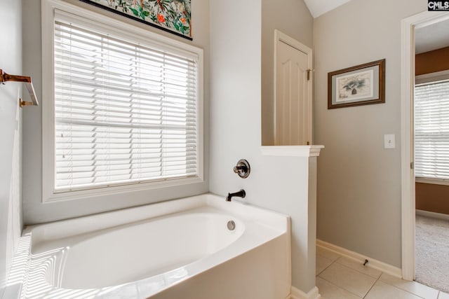 bathroom featuring tile patterned floors, baseboards, and a bath