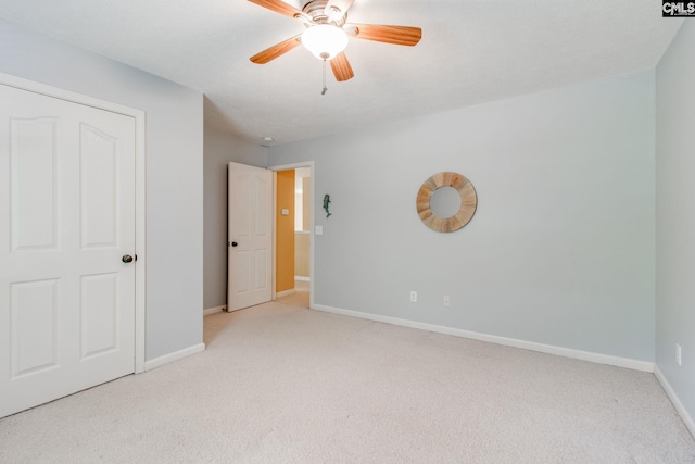 unfurnished bedroom featuring a ceiling fan, light colored carpet, and baseboards