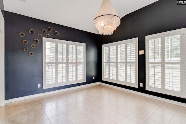 empty room with light tile patterned floors, baseboards, and an inviting chandelier