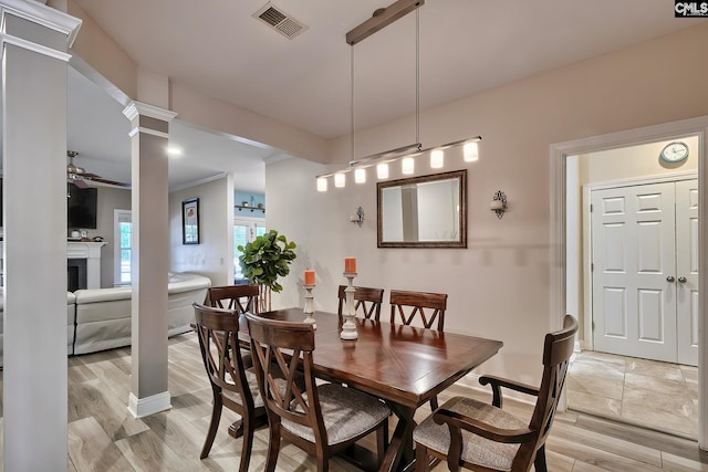 dining area featuring light hardwood / wood-style floors, ornate columns, and ceiling fan