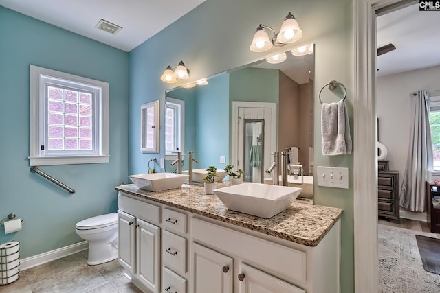 bathroom with tile patterned floors, vanity, a healthy amount of sunlight, and toilet