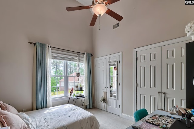 carpeted bedroom featuring ceiling fan, a high ceiling, and multiple windows