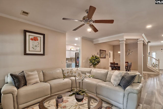 living room featuring ceiling fan, ornamental molding, and light wood-type flooring