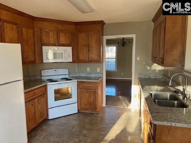 kitchen featuring light stone countertops, a textured ceiling, white appliances, sink, and a chandelier