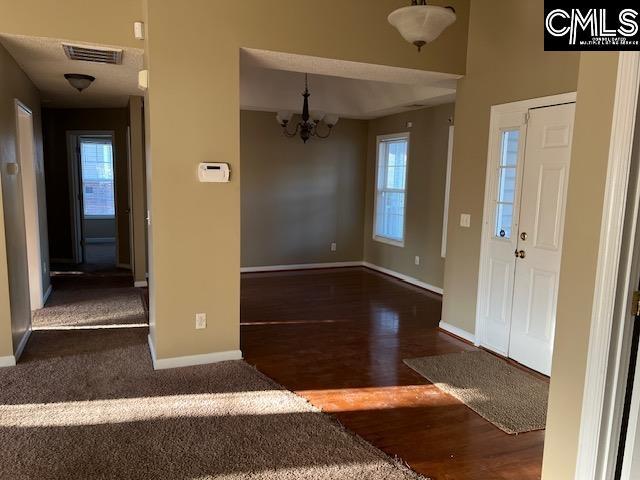 entrance foyer with dark hardwood / wood-style flooring, plenty of natural light, and a chandelier