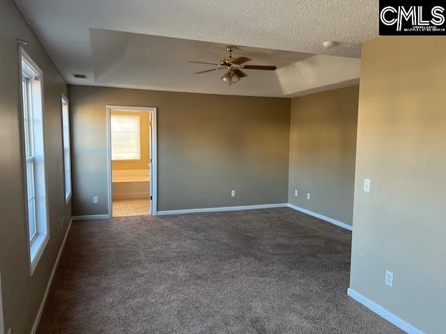 carpeted spare room featuring a tray ceiling, ceiling fan, and a textured ceiling