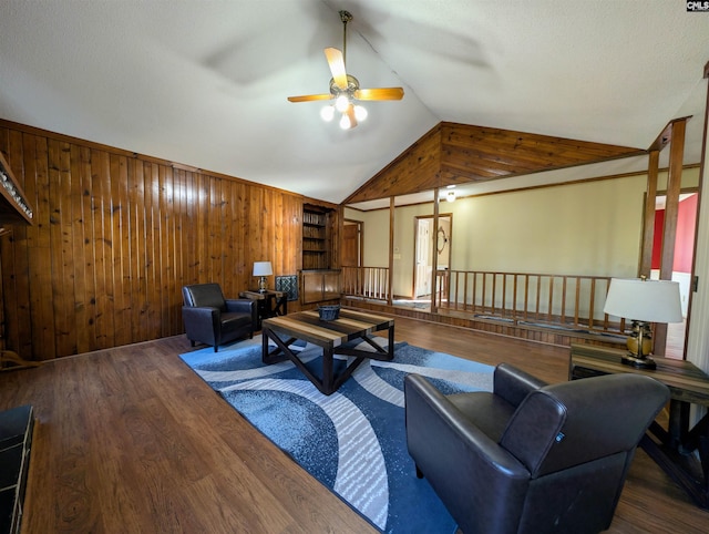 living room with wood walls, vaulted ceiling, ceiling fan, a textured ceiling, and dark hardwood / wood-style flooring