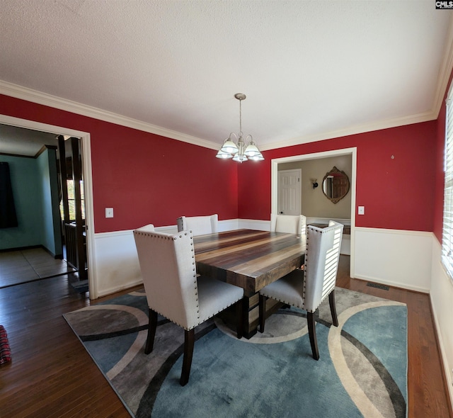 dining area featuring a textured ceiling, dark hardwood / wood-style floors, an inviting chandelier, and crown molding