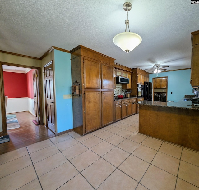 kitchen featuring black appliances, crown molding, hanging light fixtures, independent washer and dryer, and light tile patterned floors