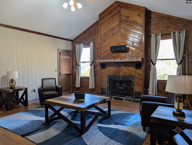 living room featuring hardwood / wood-style floors, ceiling fan, wooden walls, and vaulted ceiling