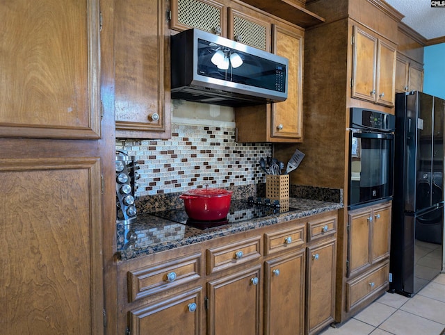 kitchen with backsplash, dark stone counters, black appliances, crown molding, and light tile patterned flooring