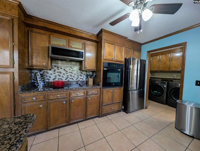 kitchen featuring backsplash, dark stone counters, black appliances, independent washer and dryer, and light tile patterned flooring