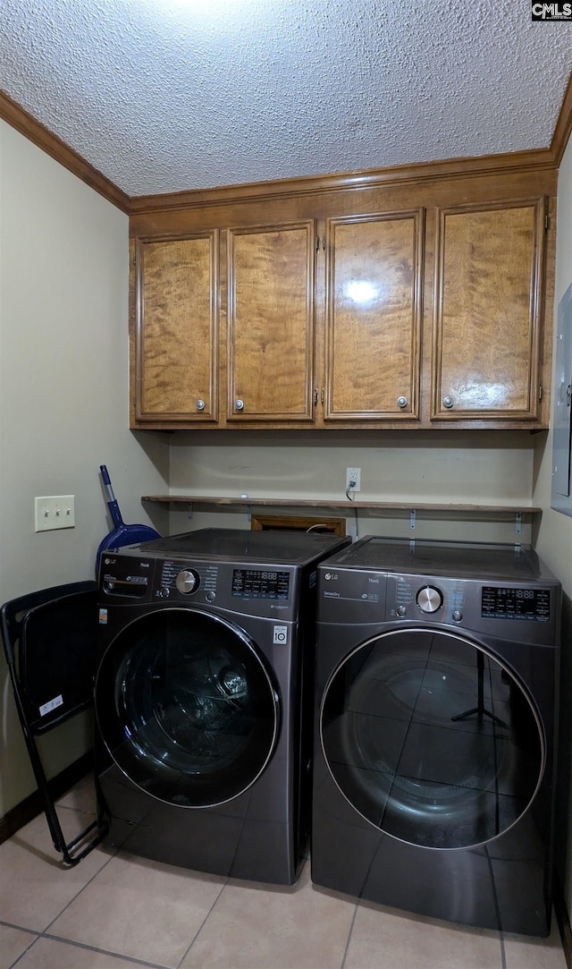 laundry room featuring cabinets, light tile patterned floors, a textured ceiling, and washing machine and dryer