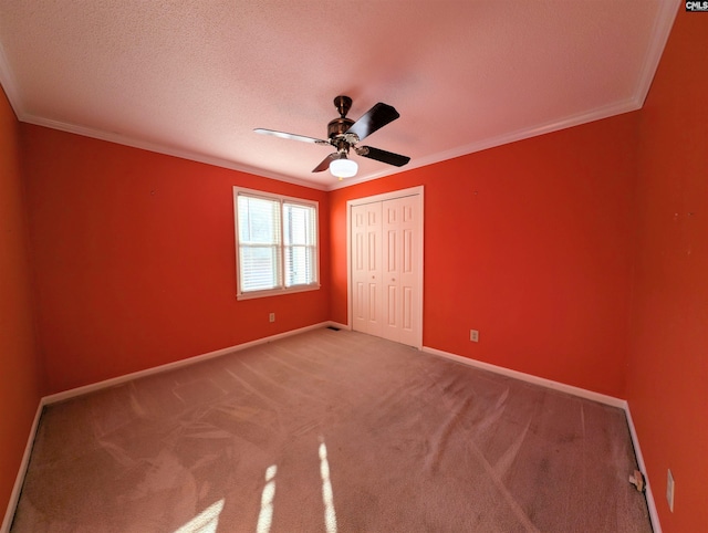 unfurnished bedroom with carpet flooring, a closet, ceiling fan, and ornamental molding