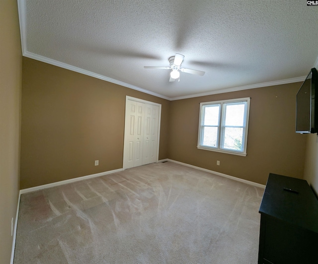 unfurnished bedroom with ceiling fan, light colored carpet, a textured ceiling, and a closet